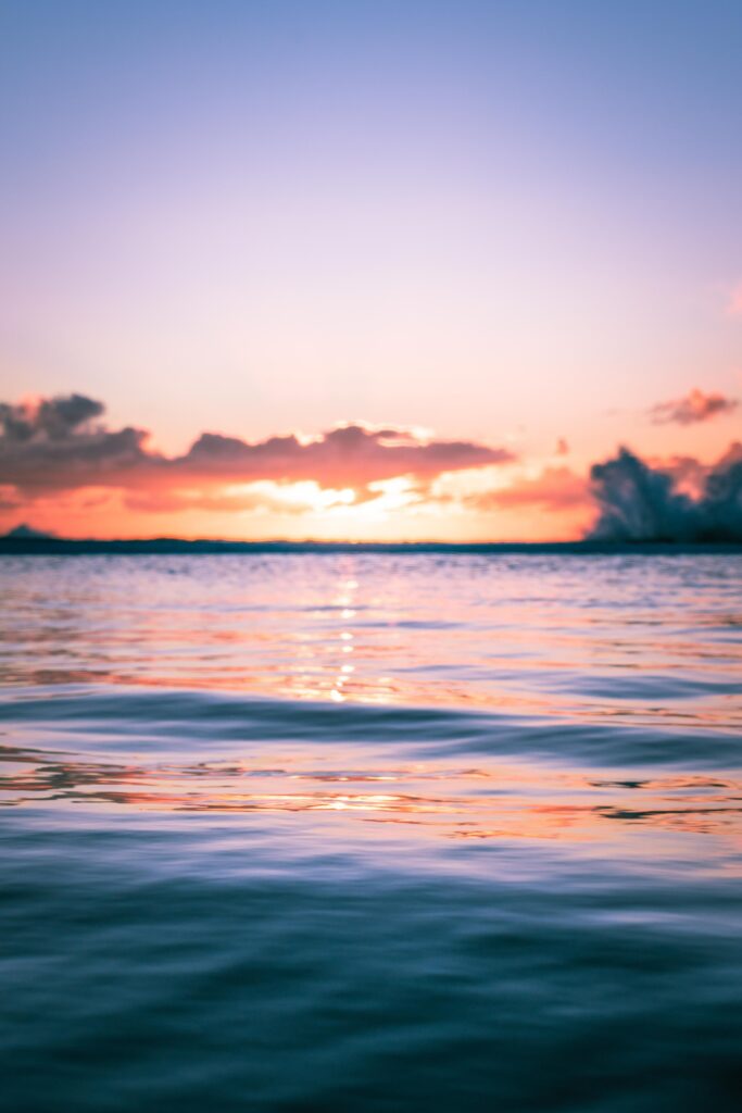 Serene sunset wallpaper with gentle water ripples reflecting pink orange and blue hues calm horizon