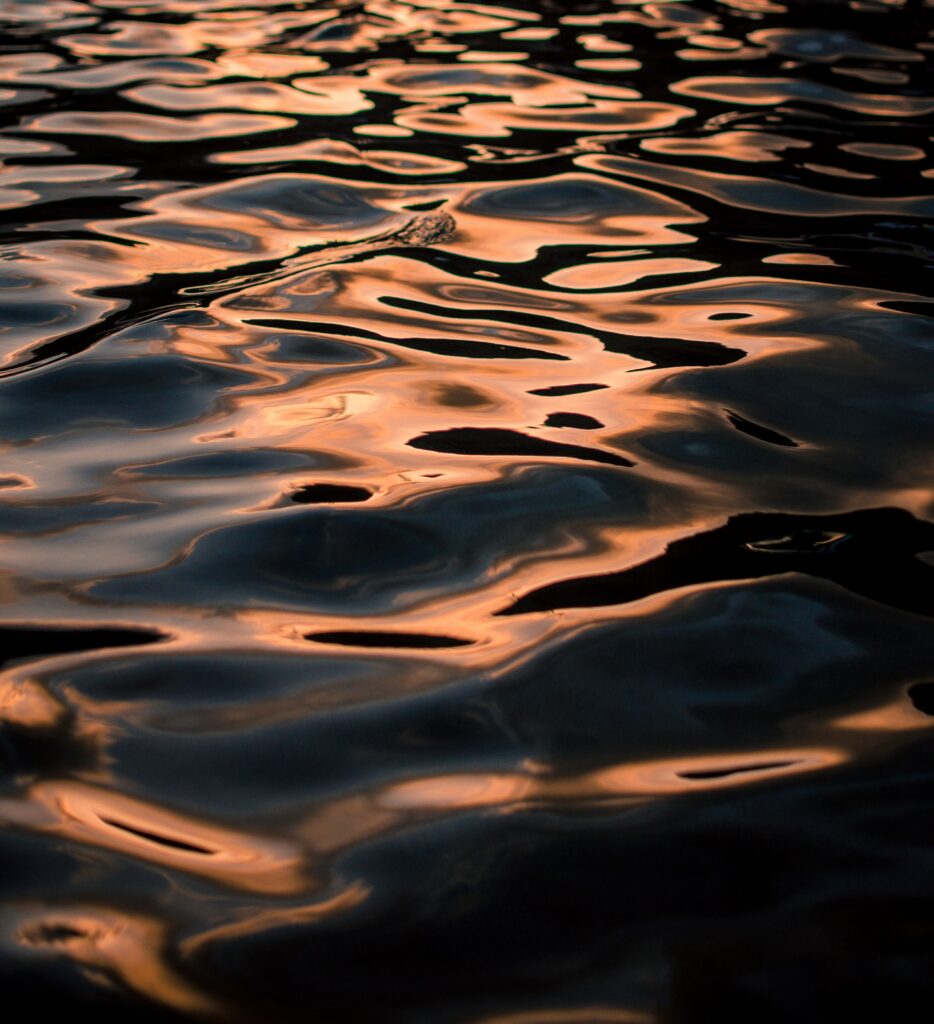 Sunset water surface wallpaper with warm golden ripples and serene abstract color reflections