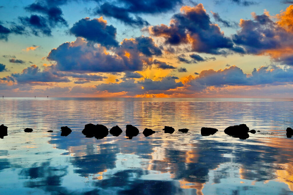 Serene sunset water scene with vibrant orange blue reflections calm surface dramatic clouds Wallpaper