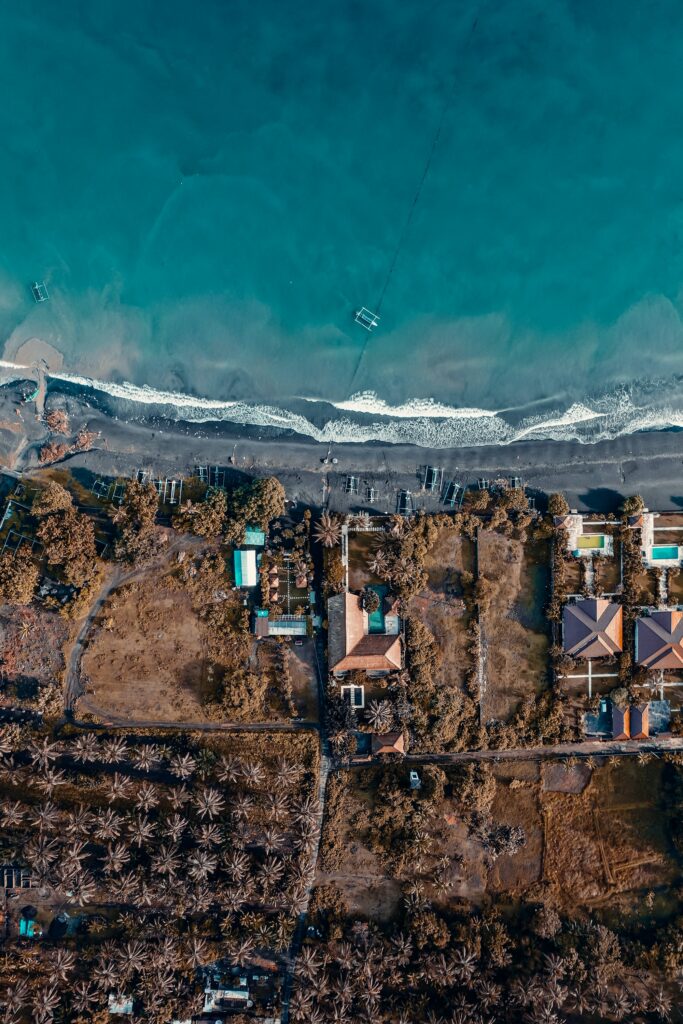 Aerial view of tropical beach with turquoise waves golden sand lush greenery and seaside villas Wallpaper