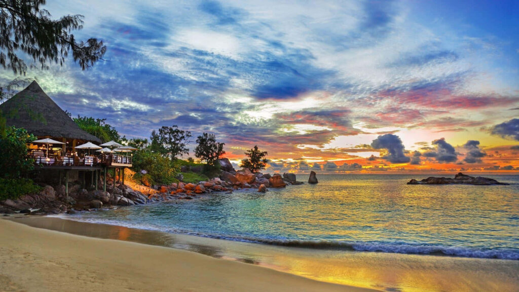 Tranquil Tropical Beach Sunset: Vibrant Sky & Serene Shoreline Wallpaper