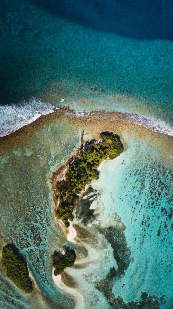 Aerial view of tropical island with turquoise water palm trees sandy beach and gentle waves wallpaper