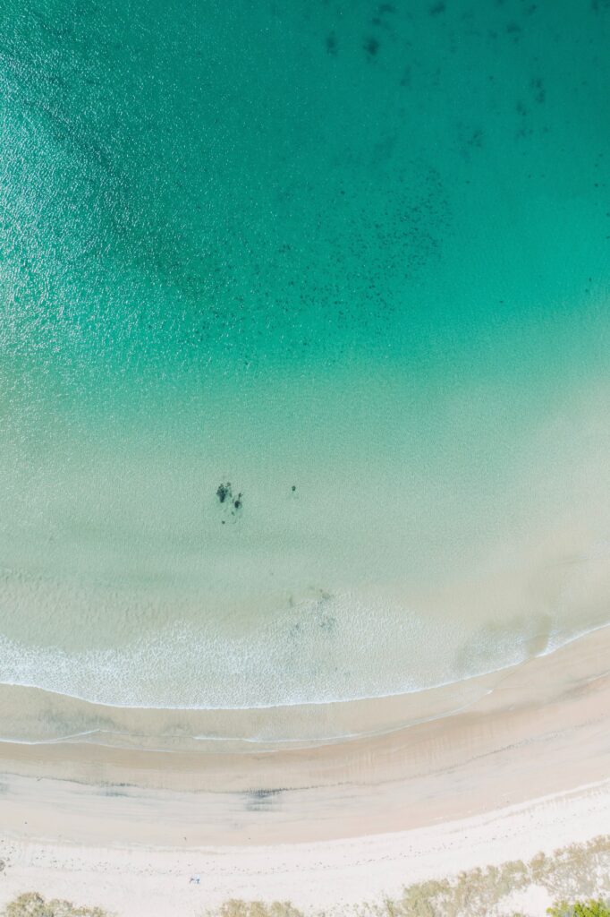 Aerial view of tranquil turquoise sea meeting soft sandy beach with gentle waves wallpaper