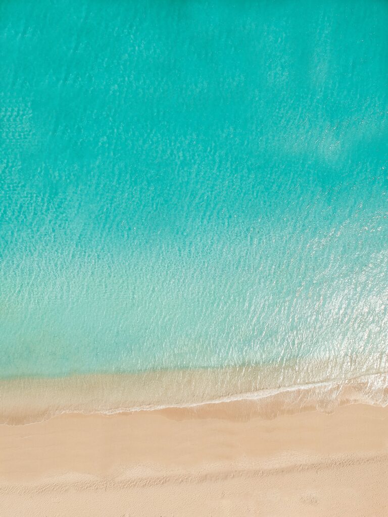 Aerial view of tranquil coastline with turquoise water meeting golden sand minimalist wallpaper