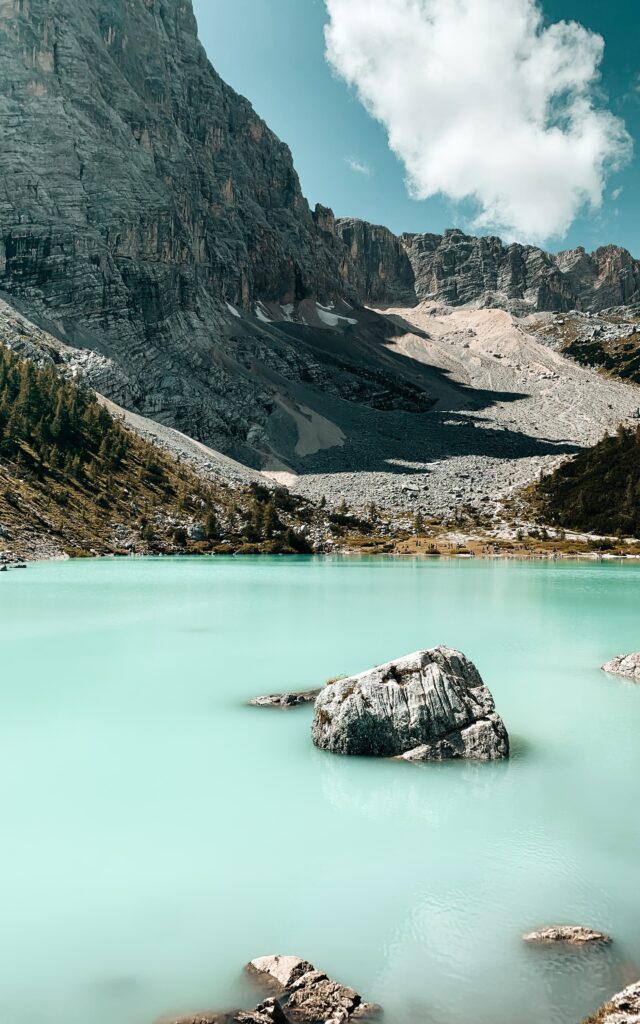 Tranquil lake with milky turquoise water rocky shore and towering mountains under clear sky wallpaper