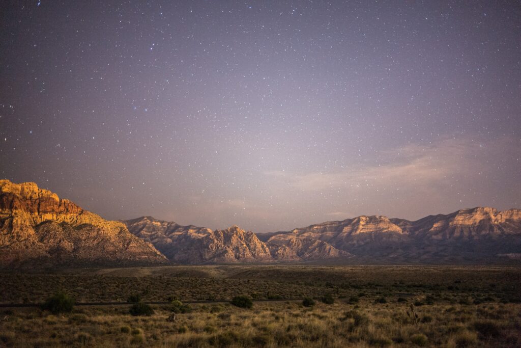 Serene plain and rugged mountains under a starry twilight sky peaceful natural landscape wallpaper