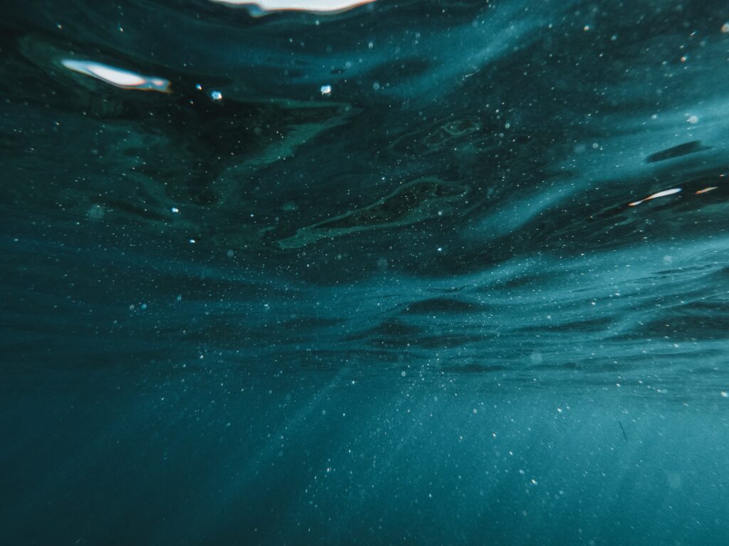 Underwater dark blue ocean wallpaper with gentle light rays and bubbles creating calm depth