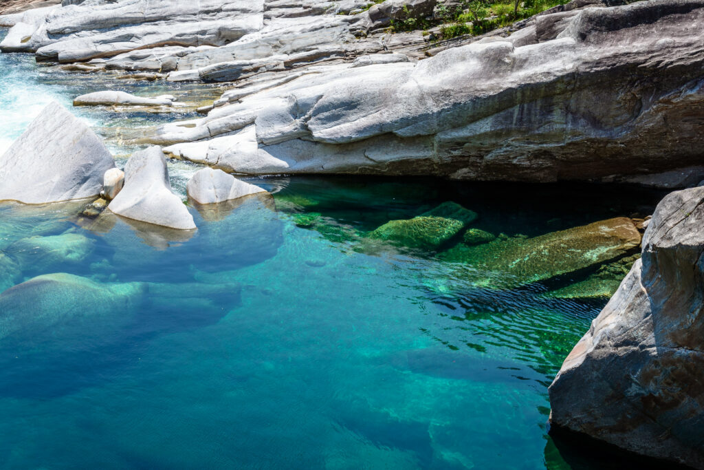 Underwater smooth stones in clear turquoise water with sunlight shimmer serene nature wallpaper