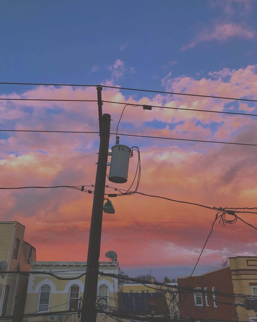 Detailed utility pole and power lines at vibrant pink and orange sunset over urban residential buildings Wallpaper