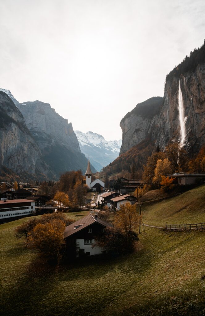 Tranquil village with church steeple autumn trees waterfall mountains cliffs wallpaper background