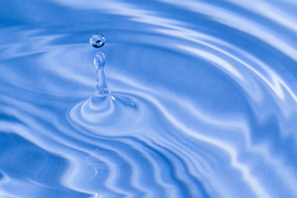 Tranquil Water Drop Macro: Ripples on Calm Blue Surface Wallpaper