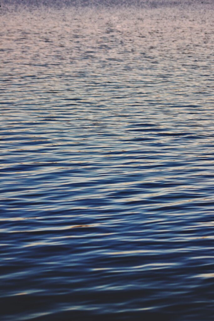 Tranquil water wallpaper with gentle ripples and soft waves in blue and pink gradient tones