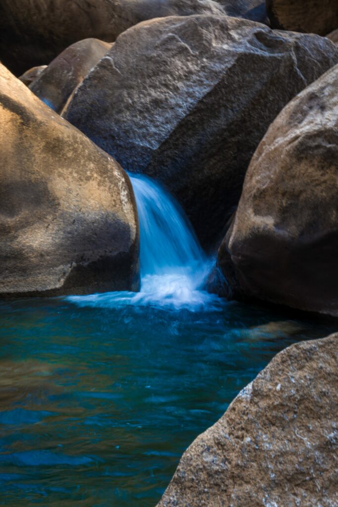 Serene nature wallpaper of blue water flowing gently over smooth earthy stones in peaceful landscape