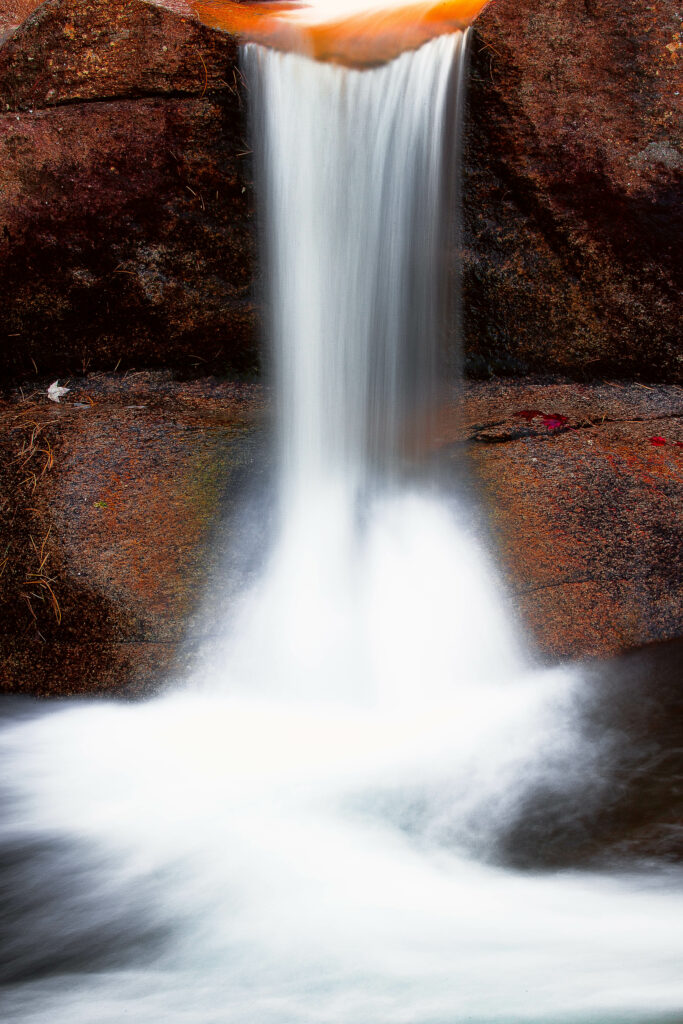 Tranquil waterfall flowing over rugged stones with silky smooth water long exposure wallpaper