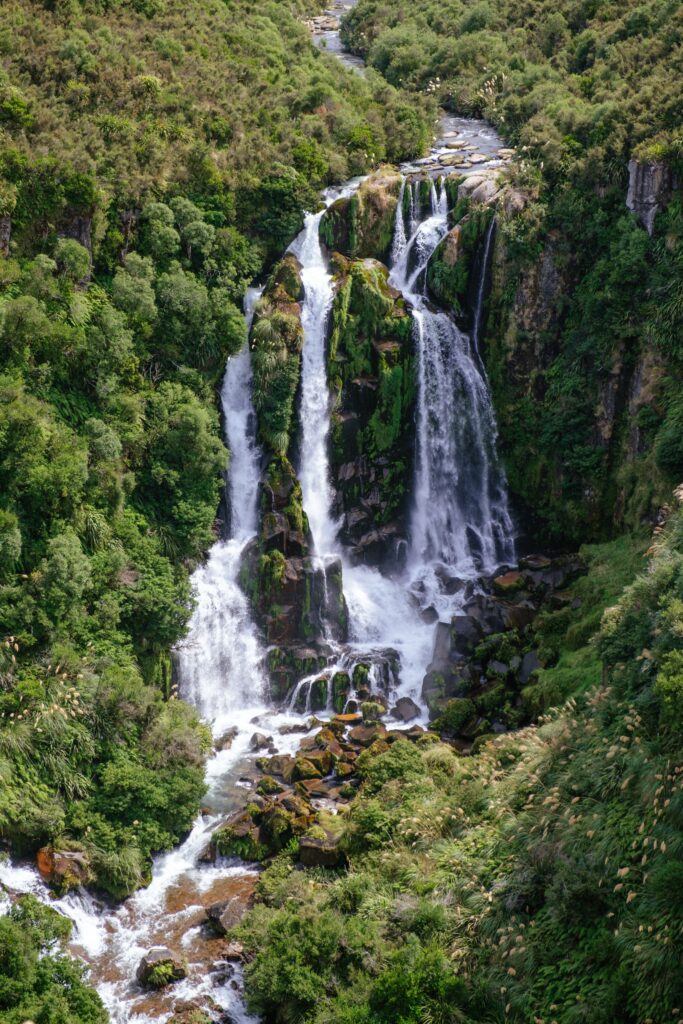 Cascading waterfall over mossy rocks in lush green forest stream natural serene wallpaper background