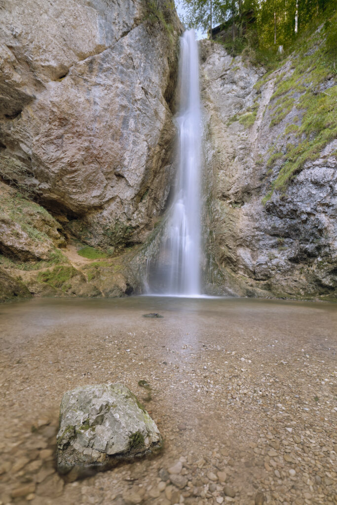 Serene waterfall flowing over rocky cliffs with clear water and smooth stones in nature wallpaper