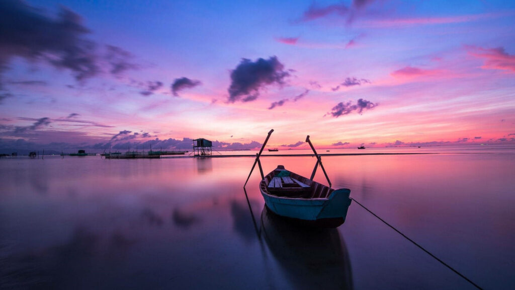 Tranquil Seascape: A Serene 4k Background Photo Featuring a Small Boat, under a Hazy Blue-Purple Sky Wallpaper