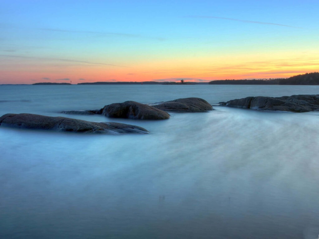 Tranquil Waters with Smooth Rocks: Serene Gradient Sky Wallpaper