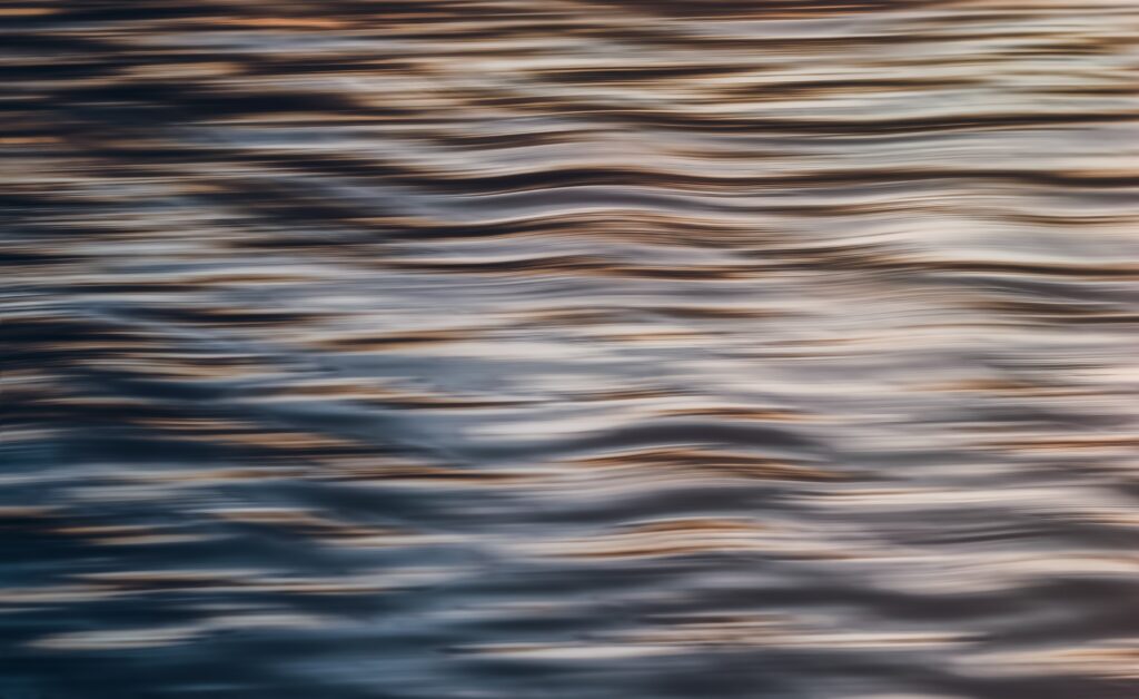 Abstract wavy water surface with gentle ripples warm cool tones tranquil soothing wallpaper background