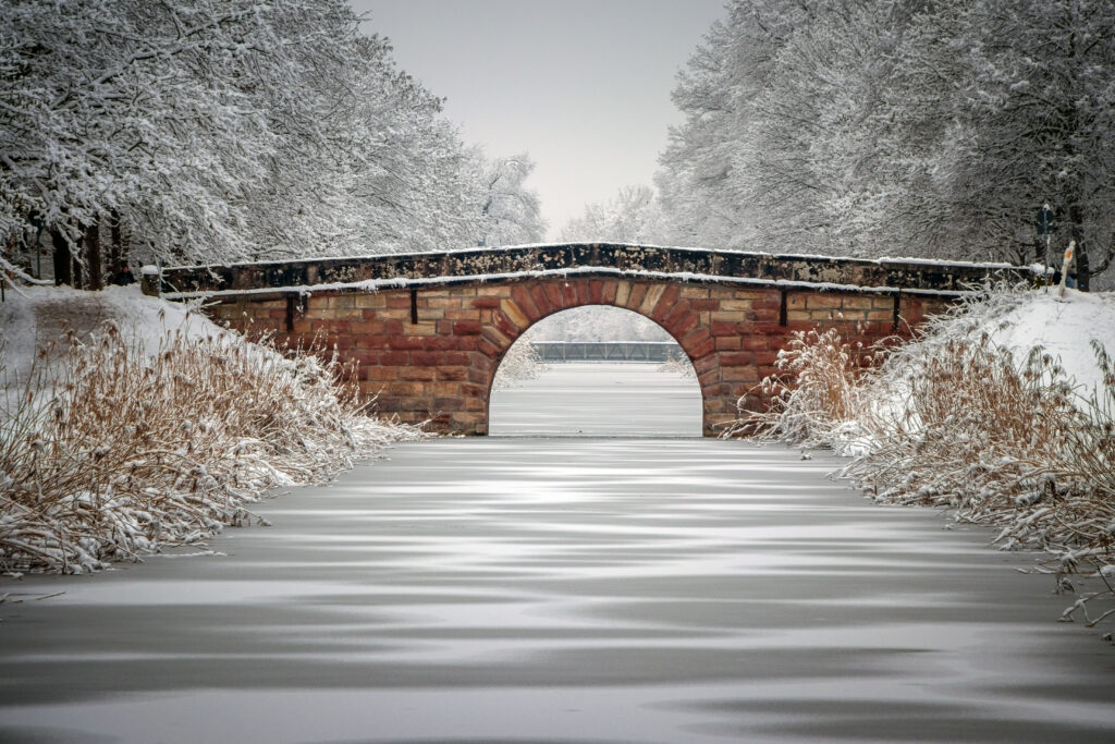 Stone bridge over frozen river snowy trees winter landscape serene peaceful wallpaper background
