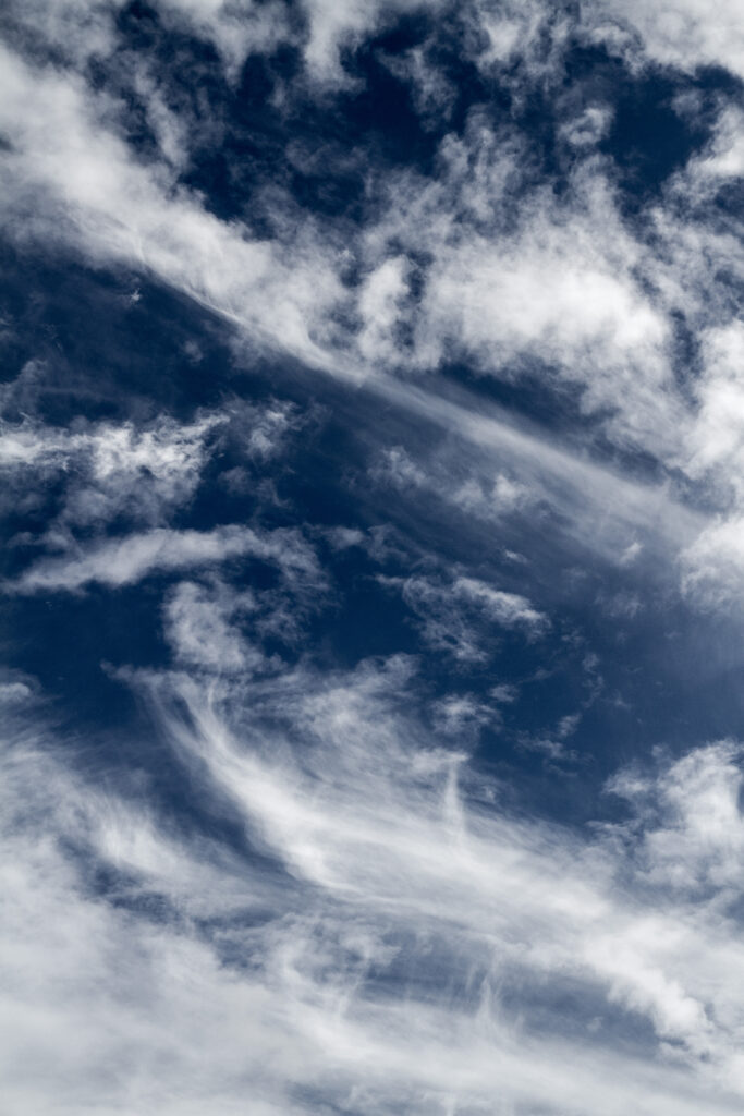 Wispy clouds drifting over deep blue sky creating airy and tranquil natural wallpaper background