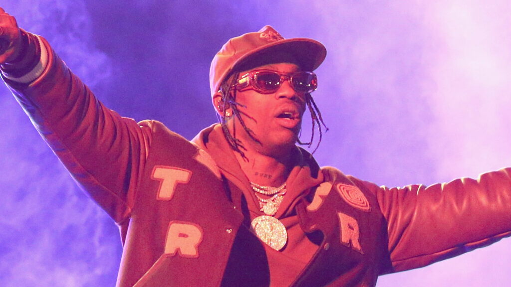 Travis Scott: Enveloped in Mysterious Fog, Sporting a Brown Dress and Cap, Adorned with Gleaming Gold Chains Wallpaper