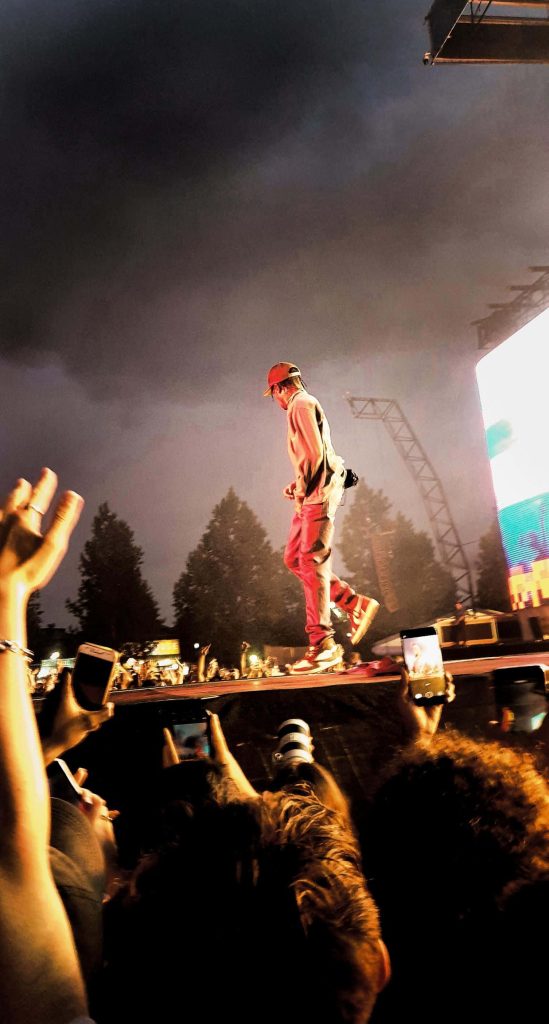 Travis Scott live concert vibrant night stage with glowing lights fans holding phones wallpaper
