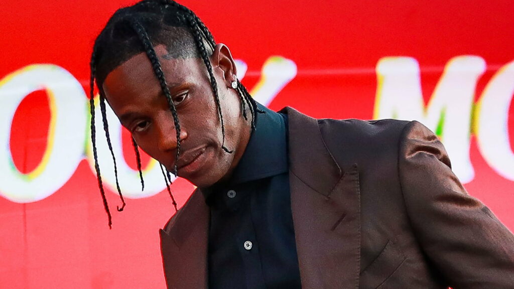 Travis Scott rocks edgy style with black shirt, brown coat, and stud earring in stunning HD wallpaper