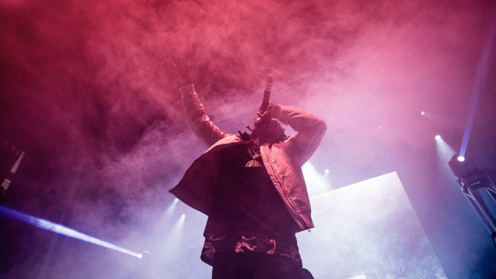 Travis Scott live concert with magenta fog and dramatic lighting intense hip hop stage shot Wallpaper