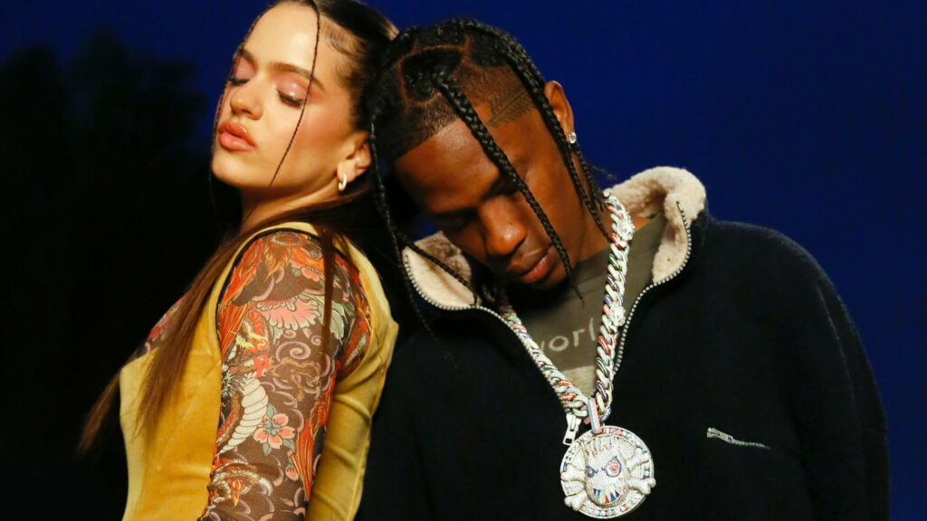 Dynamic Duo: Travis Scott and Talented Female Vocalist Pose in Matching Blue Tones Wallpaper