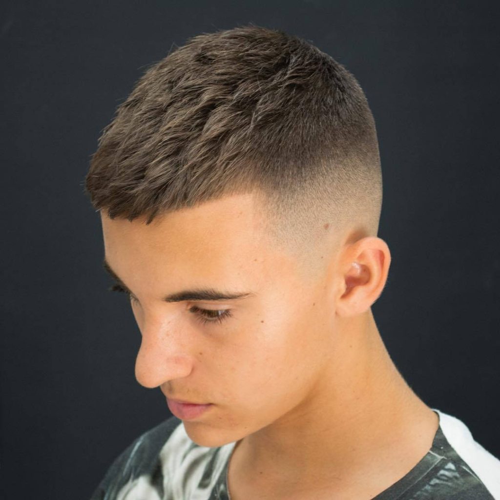 Trendy men's short fade haircut with textured crop sharp edges studio lighting background Wallpaper