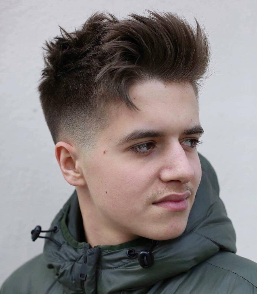 Trendy men’s textured messy hairstyle with sharp taper fade wearing olive green jacket on neutral background Wallpaper