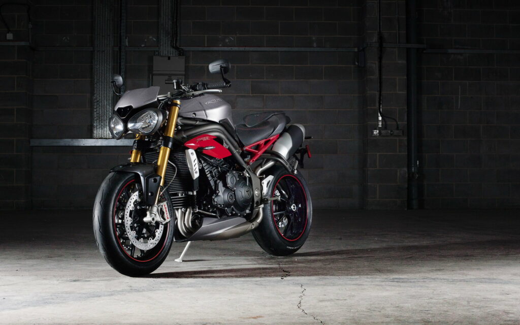 Roaring Triumph: Red Daytona Rider on Speed Triple R Bike - HD Racing Wallpaper