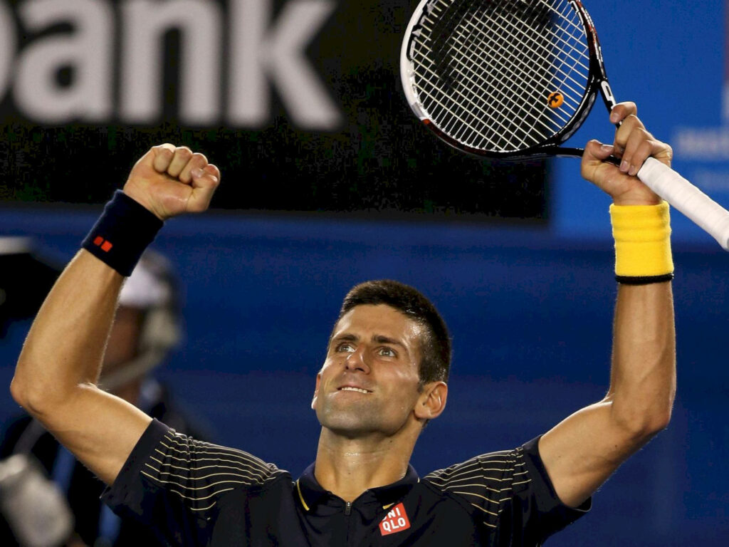 Triumphant tennis player in dark yellow-accented outfit celebrates victory under bright stadium lights Wallpaper