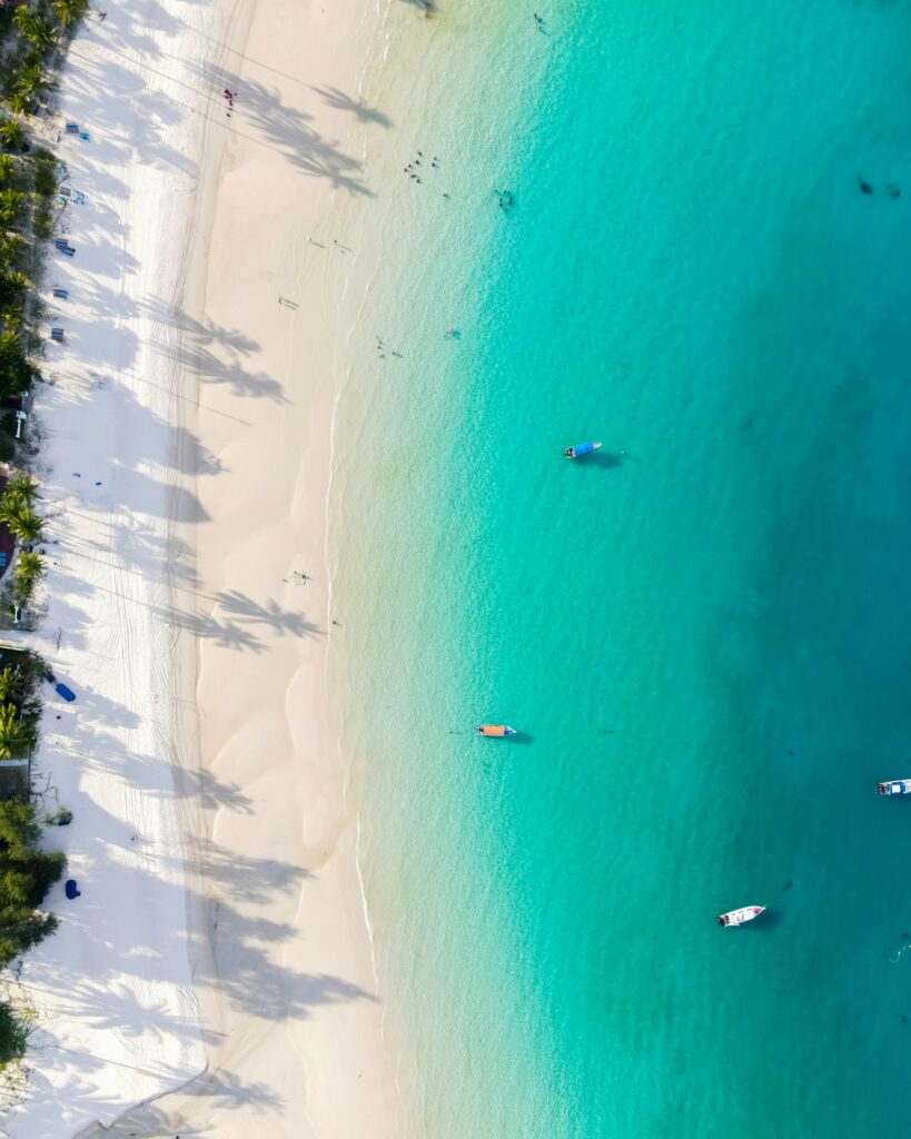 Aerial view of tropical coast with white sands turquoise sea palm shadows and colorful boats Wallpaper