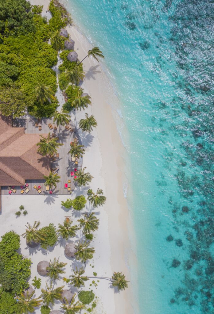 Aerial view of tropical beach with turquoise waters white sand palm trees and seaside lounge areas Wallpaper