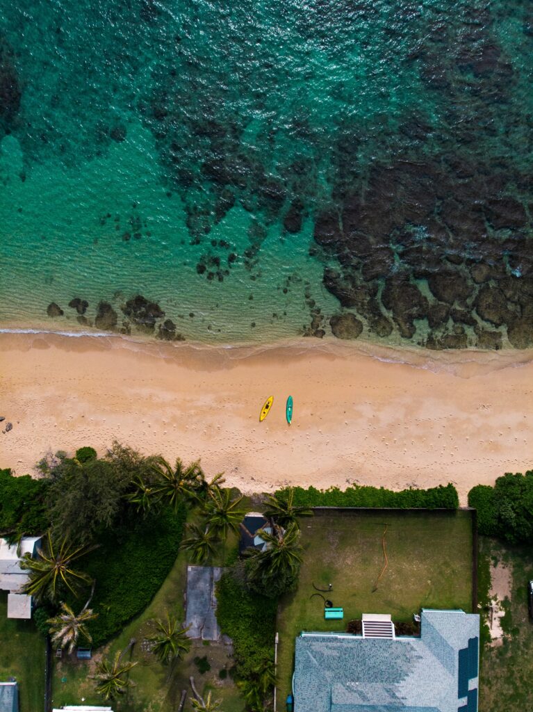 Aerial view of tropical beach with turquoise sea golden sand colorful boats palm trees and coastal homes Wallpaper