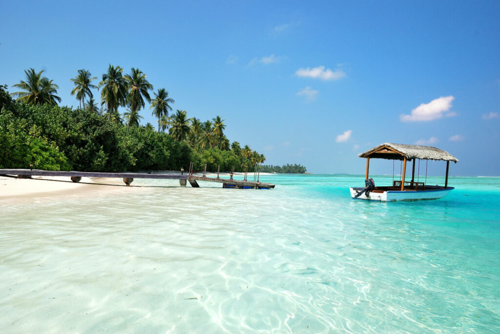 Tropical Paradise: Clear Lagoon, Rustic Boat, and Pristine Beach Wallpaper