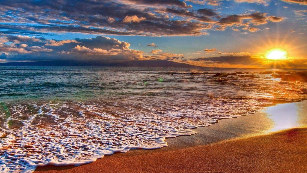 Tropical beach sunset with golden sunburst over turquoise ocean and distant island silhouette Wallpaper