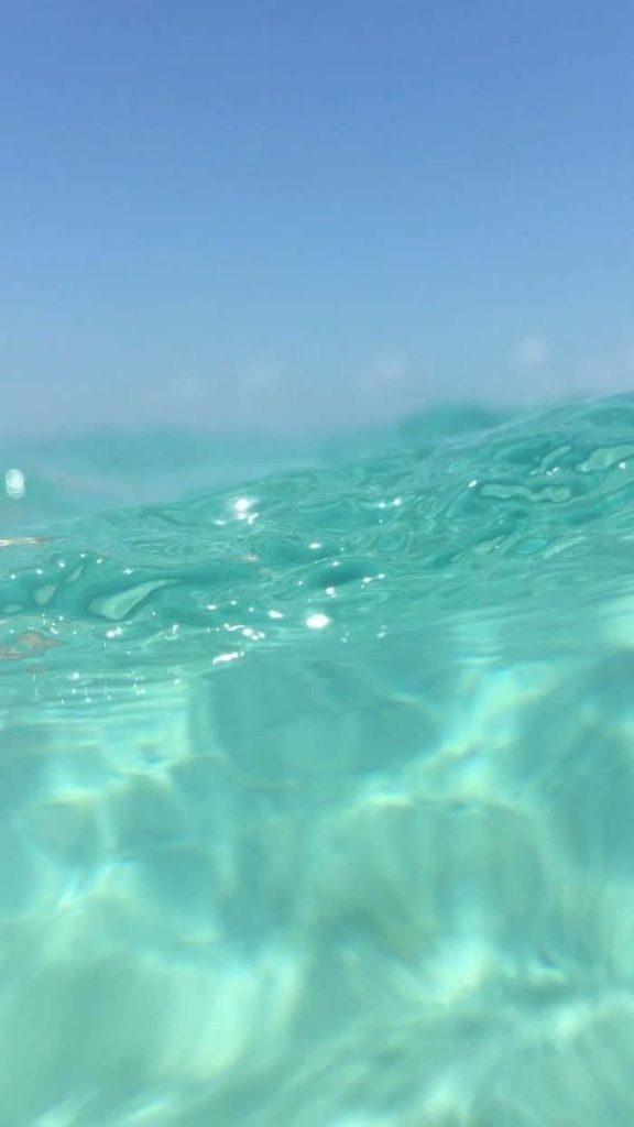 Tropical paradise split-shot blue wallpaper with clear turquoise ocean and bright sky background