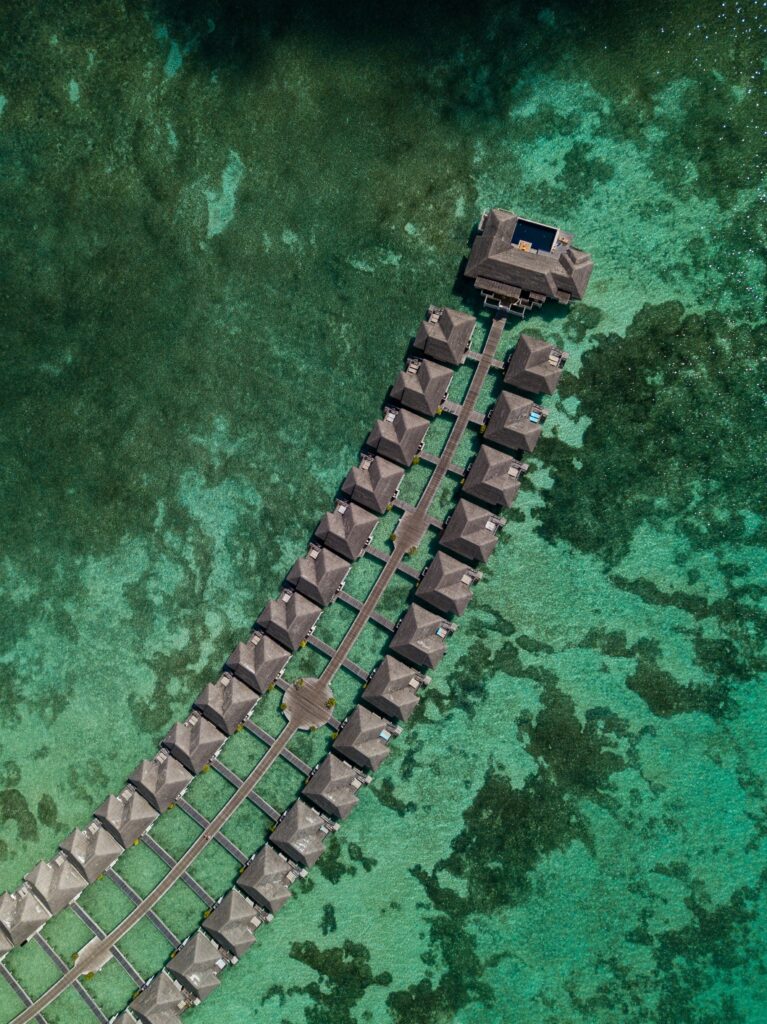 Aerial view of tropical bungalows over turquoise ocean with lush greenery and clear waters wallpaper