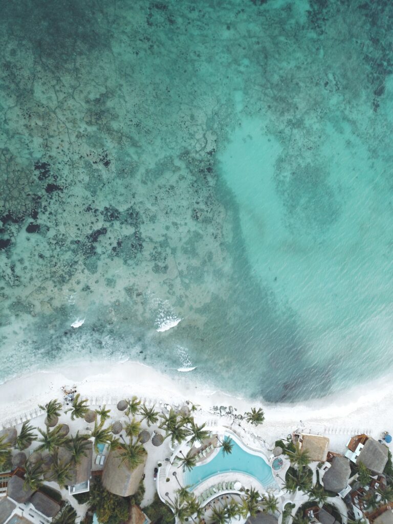 Aerial view of turquoise coastal waters with coral reefs white sandy beach palm trees tropical paradise Wallpaper