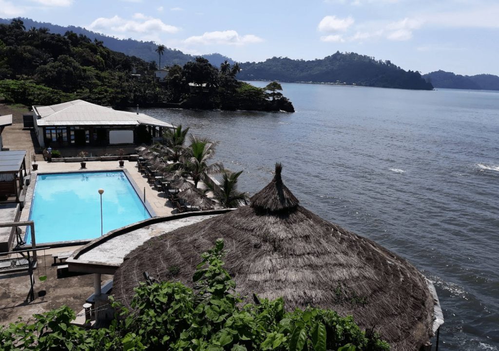 Scenic coastal resort in Limbe Cameroon with pool palm trees ocean mountain views tropical paradise Wallpaper