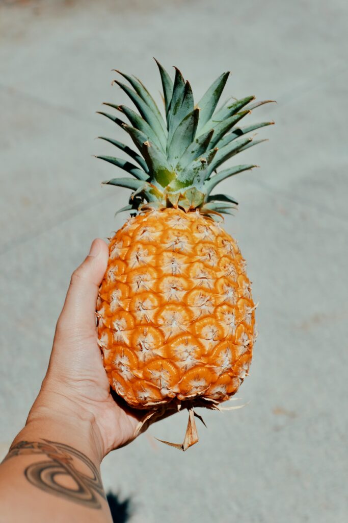 Tropical Essence: Hand Holding Fresh Pineapple Wallpaper Background