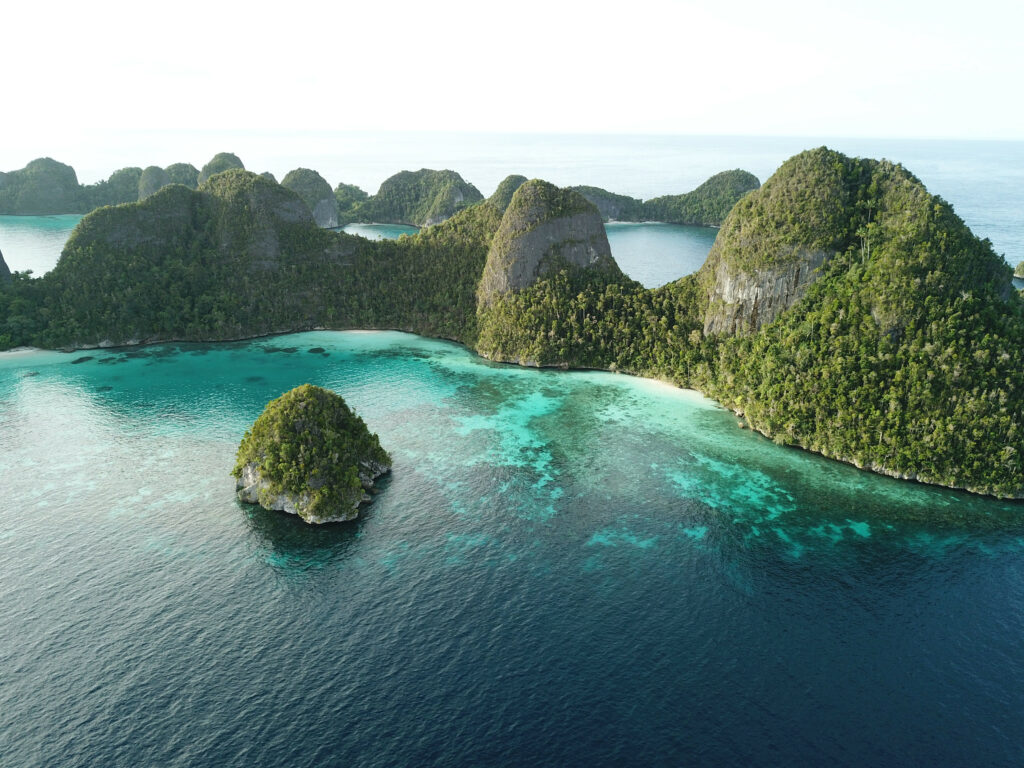 Lush green tropical islands with turquoise ocean and limestone formations under bright sky wallpaper