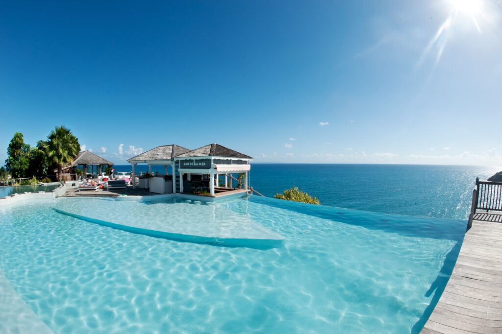 Tropical wallpaper with infinity pool palm trees island buildings and blue sea under sunny sky