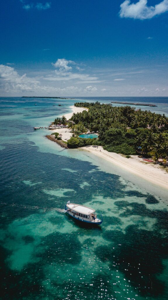 Aerial view of tropical island with turquoise sea white sand boats palm trees bright blue sky Wallpaper