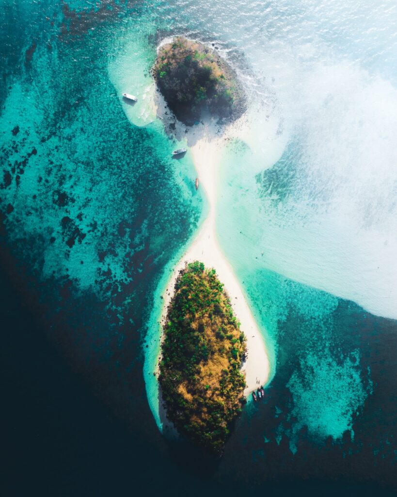 Aerial view of tropical island with turquoise sea two sandy islets boats and lush greenery wallpaper