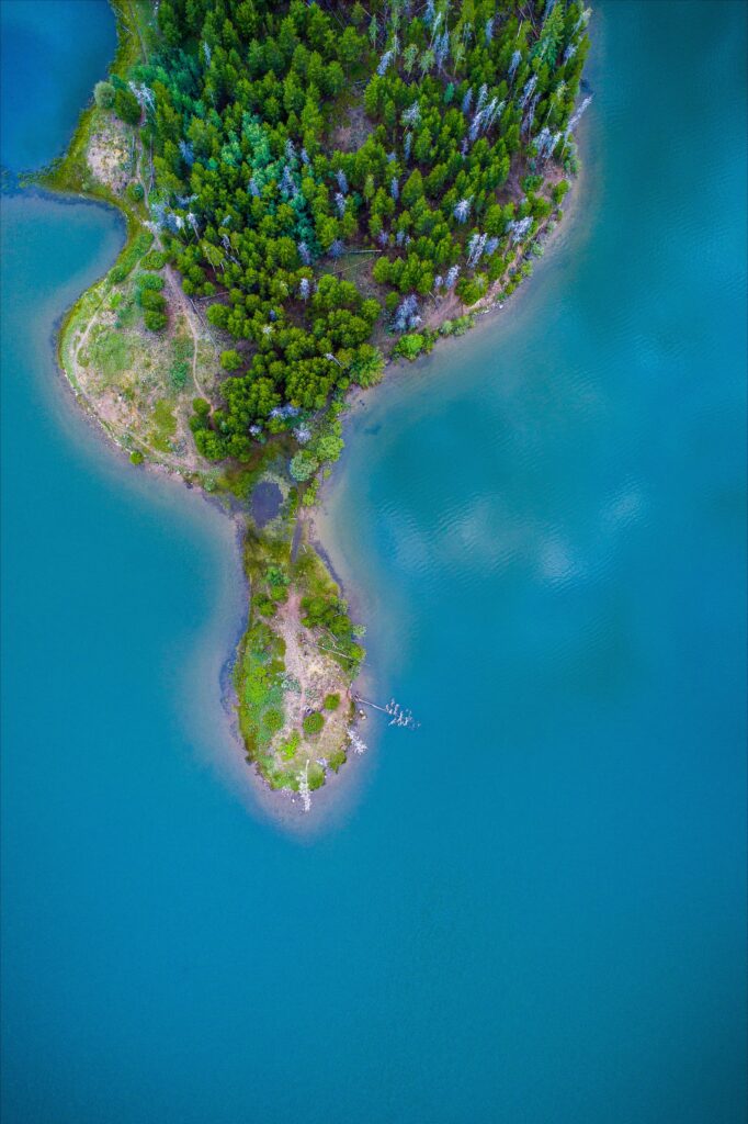 Aerial view of lush green island surrounded by vibrant blue ocean waters scenic wallpaper background