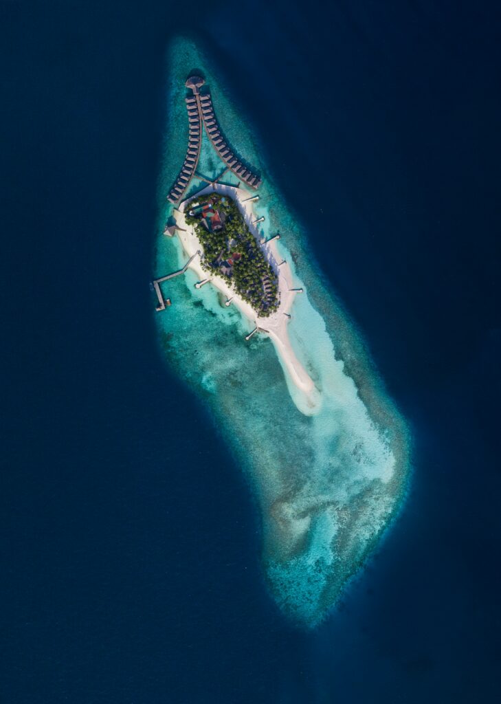 Aerial view of tropical island with turquoise waters sandy beaches lush greenery and overwater villas Wallpaper
